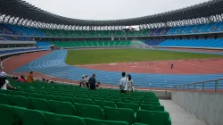 Bagian dalam Kaohsiung National Stadium dengan kursi hijau dan biru mengelilingi lintasan lari serta lapangan rumput