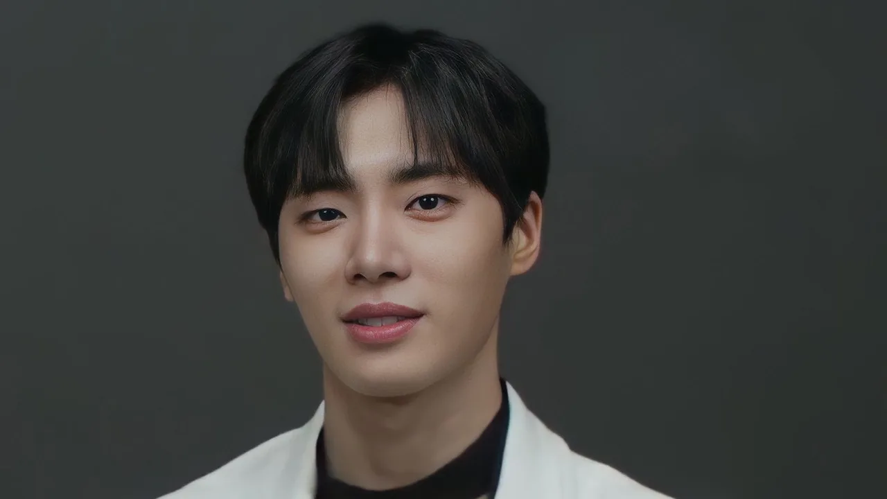 Choo Young-woo tersenyum mengenakan jas putih dengan latar abu-abu