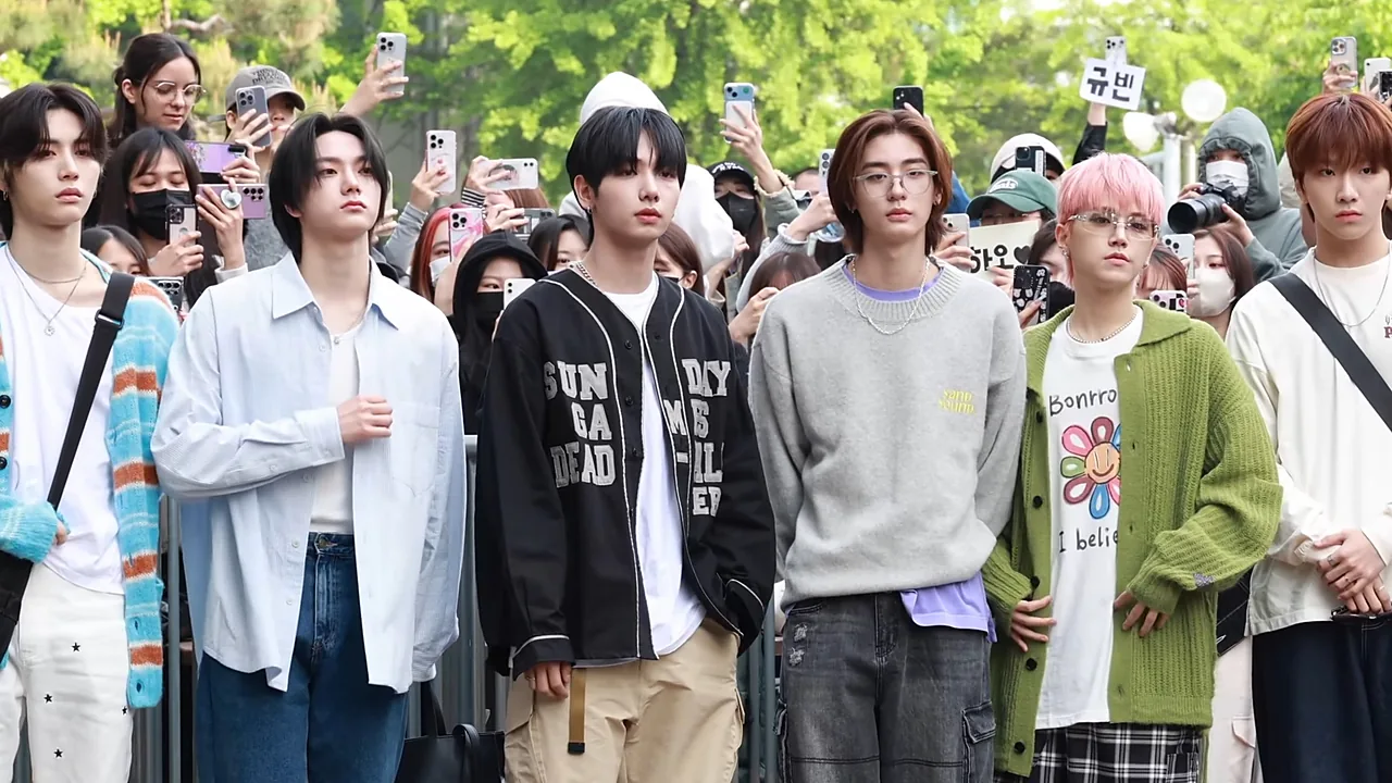 Enam personel BOYNEXTDOOR berjalan menuju gedung Music Bank dikelilingi penggemar