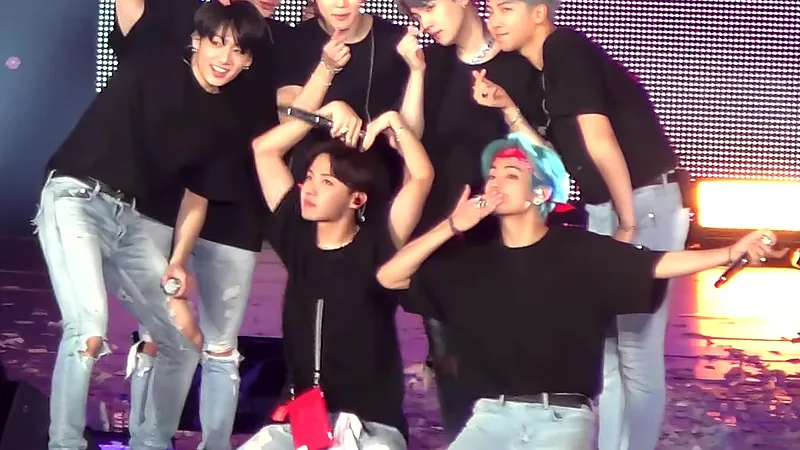 Personel BTS berpose bersama mengenakan kaus hitam di atas panggung konser