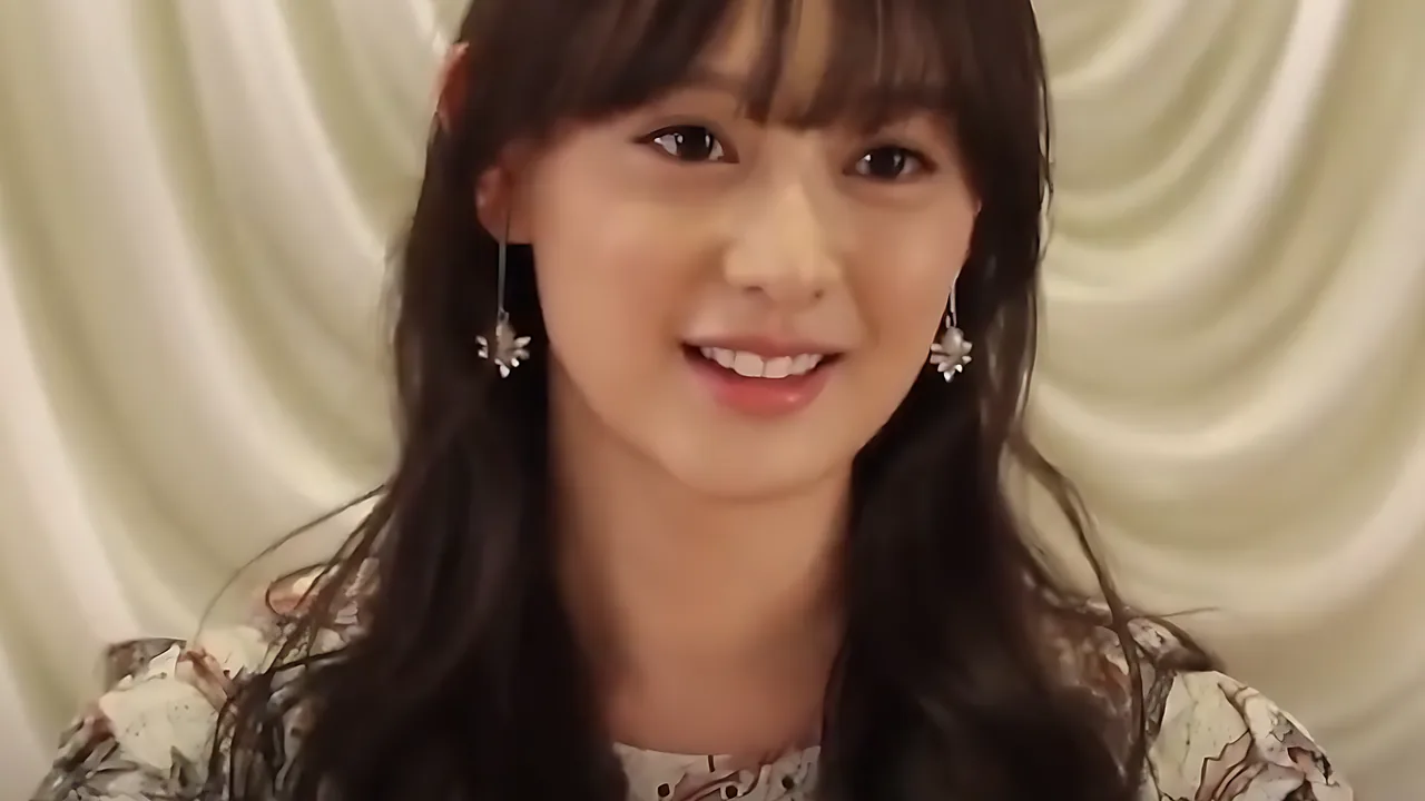 Kim Ji-won tersenyum dengan anting panjang berlatar tirai krem