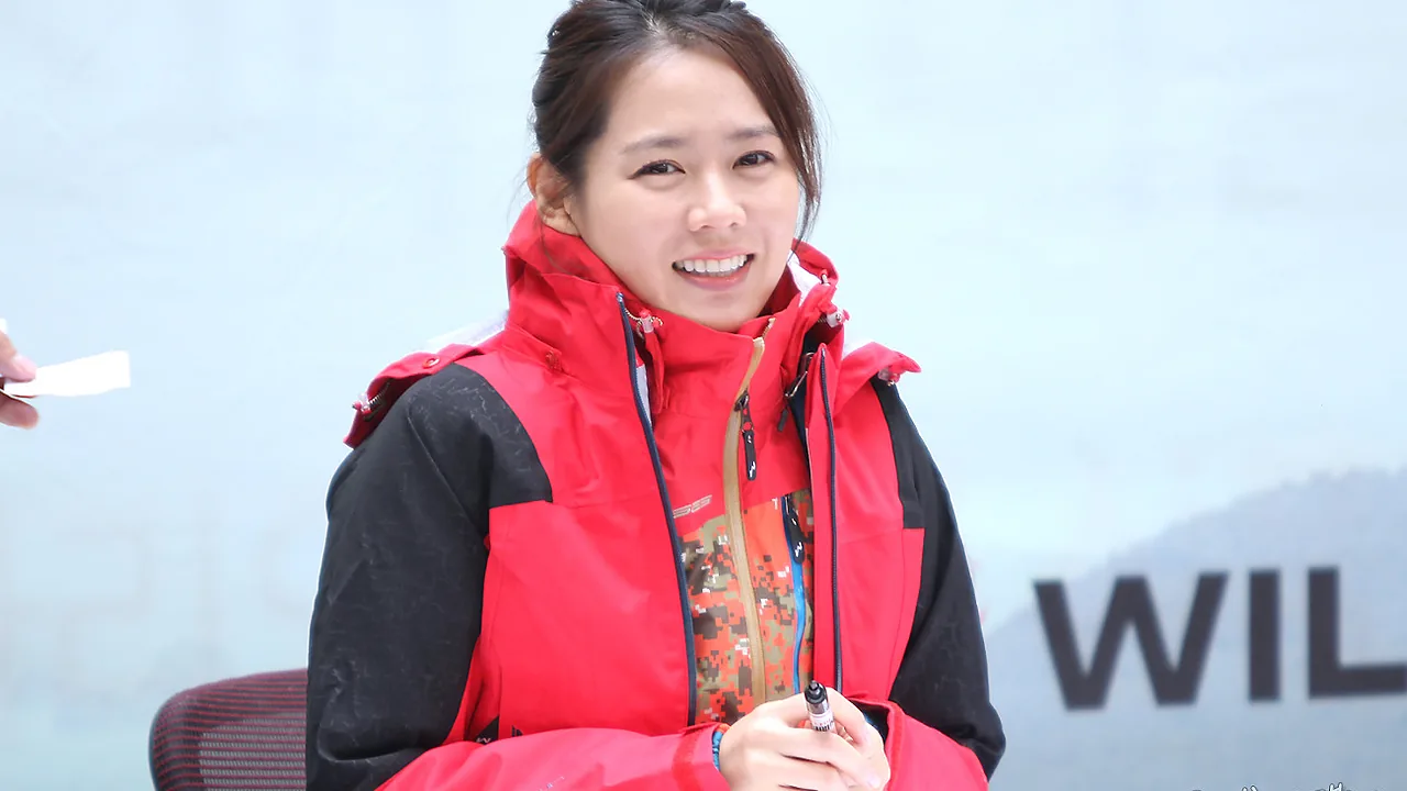 Son Ye-jin tersenyum mengenakan jaket outdoor merah pada acara jumpa penggemar