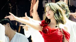 IU bergaun merah menunjuk ke arah penonton di panggung konser HEREH