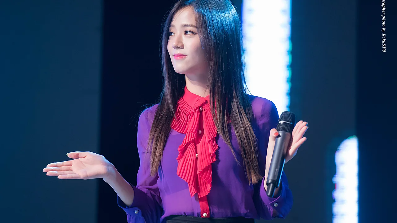 Jisoo BLACKPINK berkemeja ungu dengan pita merah memegang mikrofon di panggung