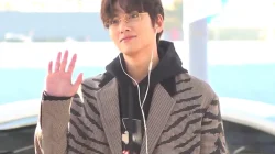 Ji Chang-wook berkacamata melambaikan tangan dengan mantel motif garis di bandara