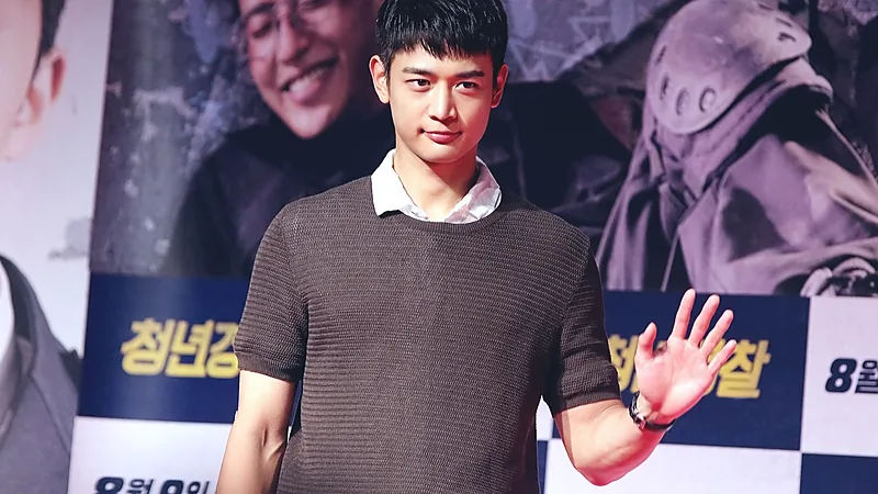 Choi Minho SHINee mengenakan atasan rajut cokelat melambaikan tangan di premier film