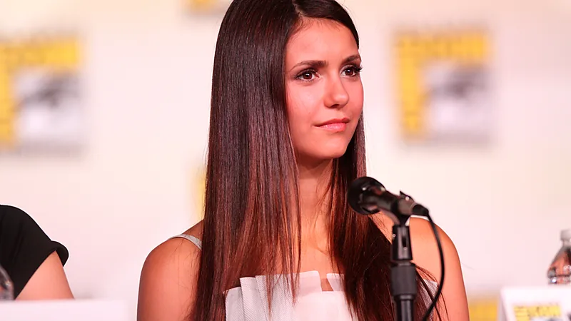 Nina Dobrev berambut panjang mengenakan gaun putih di panel Comic-Con