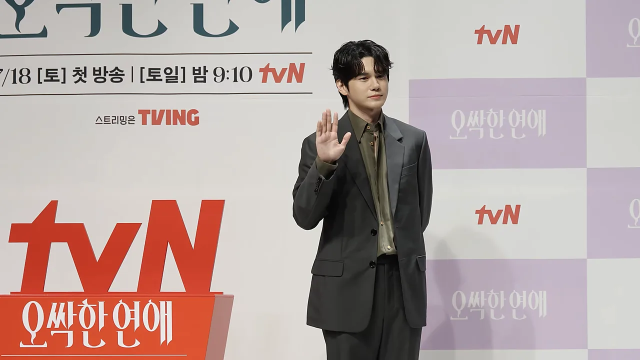 Ong Seong-wu melambaikan tangan dengan setelan abu-abu di jumpa pers tvN
