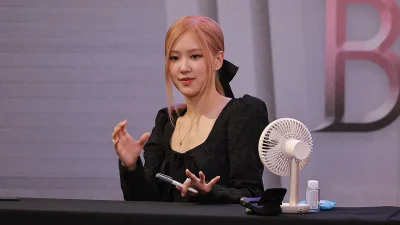 Rosé BLACKPINK berbicara sambil menggerakkan tangan di meja acara fan signing