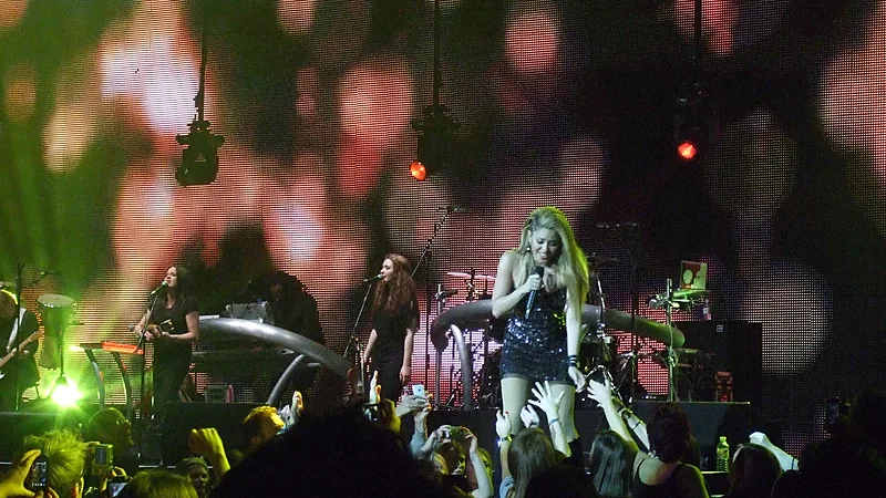 Shakira bernyanyi dengan gaun berkilau di atas panggung konser
