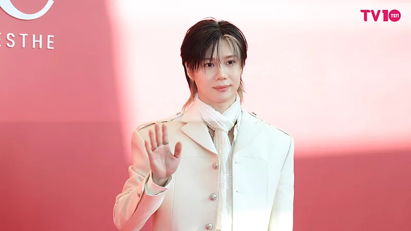 Taemin berpose melambaikan tangan dengan jas putih di sebuah acara