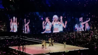Personel TWICE melambai ke penonton arena dengan layar raksasa di konser This Is For Vancouver