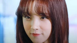 Potret dekat Song Yuqi, anggota i-dle, berambut merah kecokelatan sedang tersenyum tipis menghadap kamera