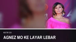 Agnez Mo bergaun merah muda berdiri di karpet merah, dengan teks Agnez Mo ke Layar Lebar