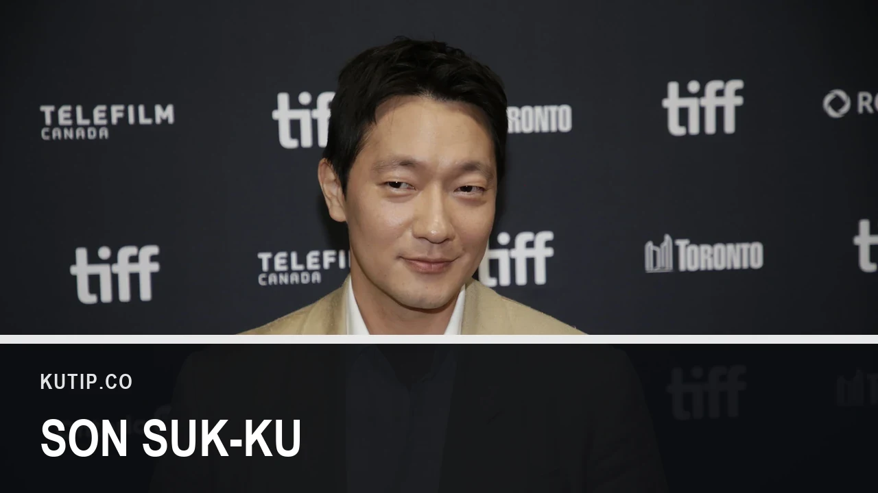 Aktor Son Suk-ku berjas krem di depan dinding sponsor Toronto International Film Festival pada September 2026, dengan nama Son Suk-ku tertulis pada palang di bagian bawah gambar