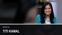 Aktris Titi Kamal mengenakan busana biru dalam sebuah program televisi, ditempatkan di sisi kanan bingkai dengan latar buram dari foto yang sama, dengan nama Titi Kamal tertulis pada palang di bagian bawah gambar