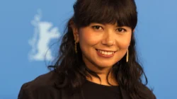 Potret sutradara Kamila Andini tersenyum di depan dinding biru Berlinale