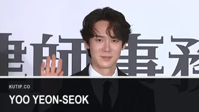 Aktor Yoo Yeon-seok berjas hitam melambaikan tangan di acara jumpa pers pada Maret 2026, dengan nama Yoo Yeon-seok tertulis pada palang di bagian bawah gambar