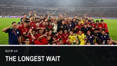 Pemain dan ofisial Timnas Indonesia berfoto bersama di lapangan stadion yang penuh penonton, dengan teks The Longest Wait